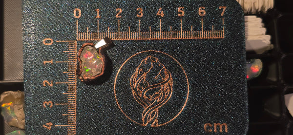 Raw uncut Ethiopian Welo opal pendant. Colour: full rainbow, moderate, soft and creamy. Body: crystal clear. Placed next to a steel ruler for scale.