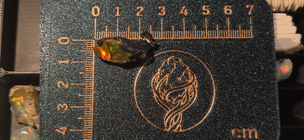 Raw uncut Ethiopian Welo opal pendant with huge red & orange flashes. Placed next to a steel ruler for scale.