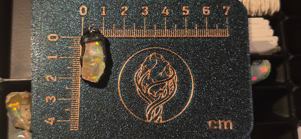 Raw uncut Ethiopian Welo opal pendant with multicolour fire throughout. Placed next to a steel ruler for scale.