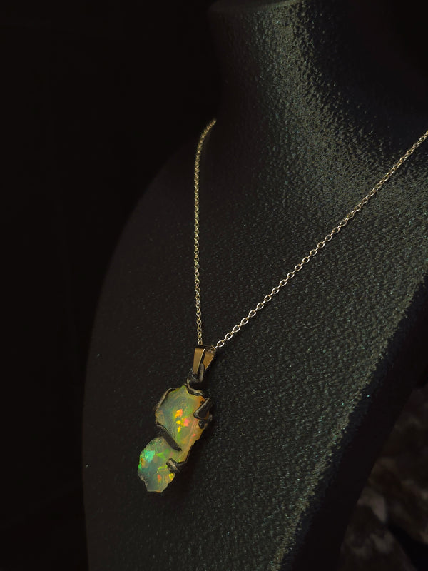 Raw uncut Ethiopian Welo opal pendant, shifting rainbow fire. Worn on a black display bust.