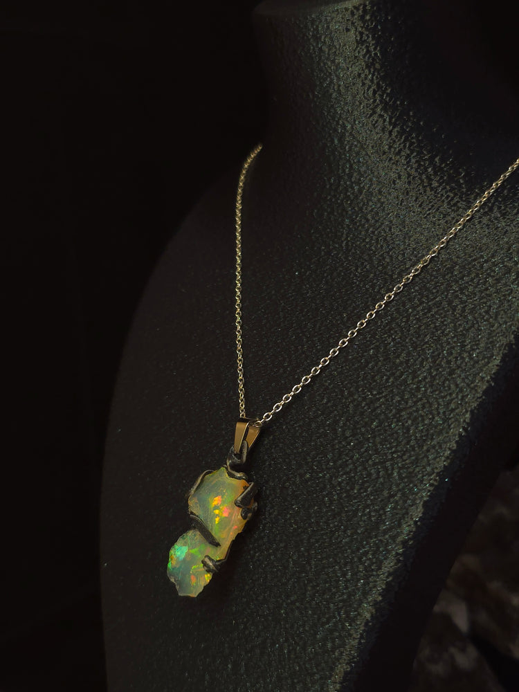 Raw uncut Ethiopian Welo opal pendant, shifting rainbow fire. Worn on a black display bust.
