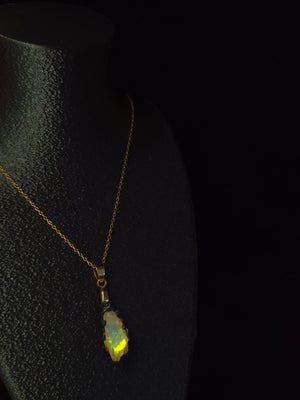 Raw uncut Ethiopian Welo opal pendant, green flashes on light blue. Worn on a black display bust.