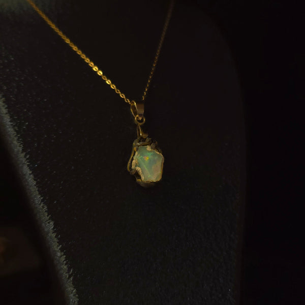 Raw uncut Ethiopian Welo opal pendant. Colour: green and red, strong. Body: light blue. Worn on a black display bust.