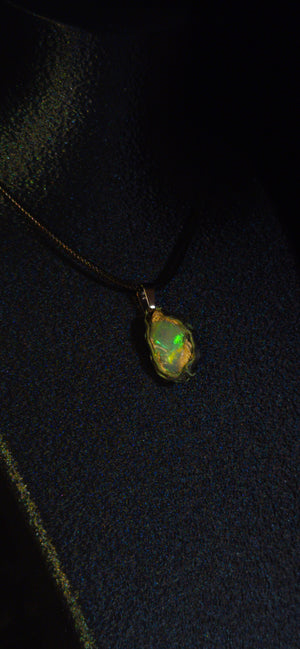 Raw uncut Ethiopian Welo opal pendant. Colour: green and blue, strong. Body: clear, light blue. Worn on a black display bust.
