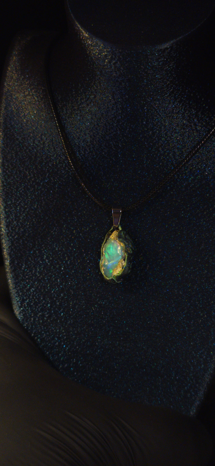 Raw uncut Ethiopian Welo opal pendant. Colour: green and blue, strong. Body: clear, light blue. Worn on a black display bust.